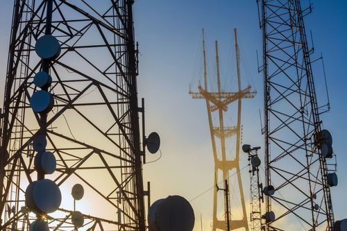 Torres de comunicación y antenas recortadas contra el cielo del atardecer.
