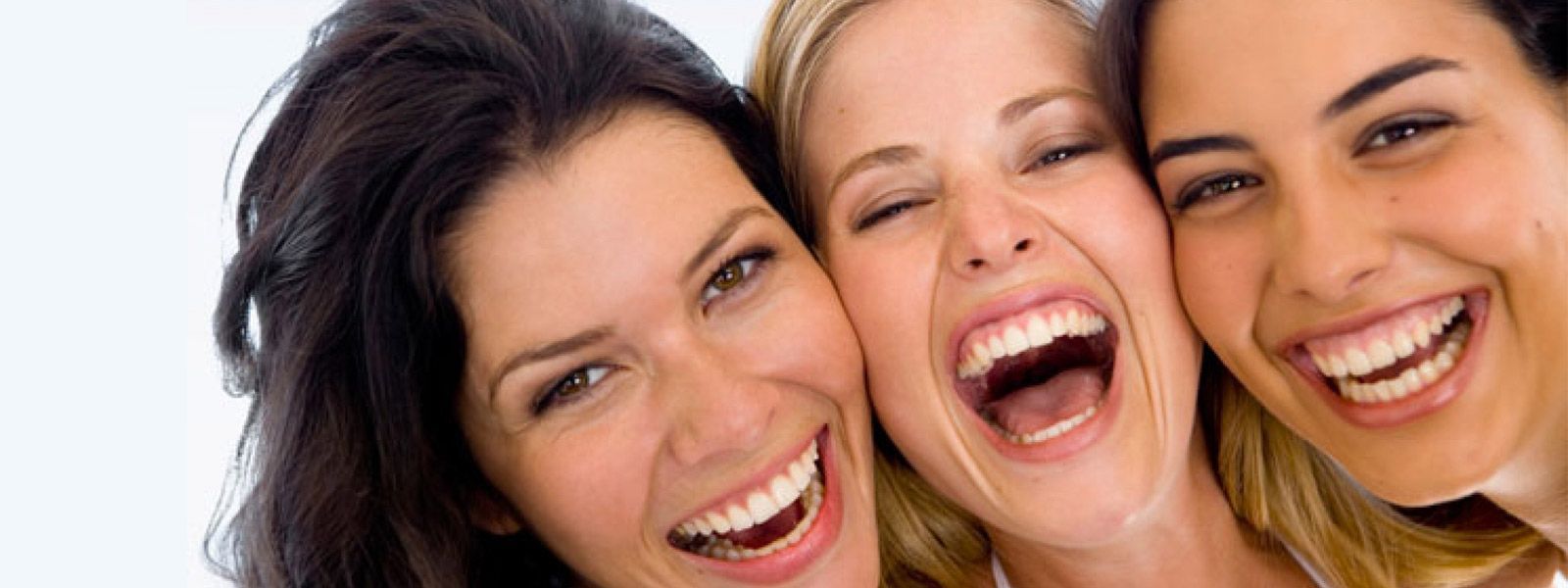 Tres personas sonrientes, muy juntas, riendo sobre un fondo claro.