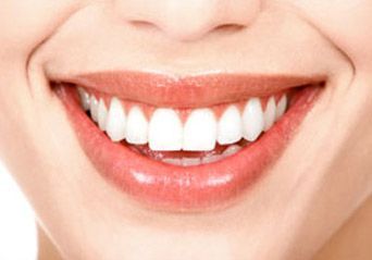 Primer plano de una boca sonriente con dientes blancos y labios rosados.