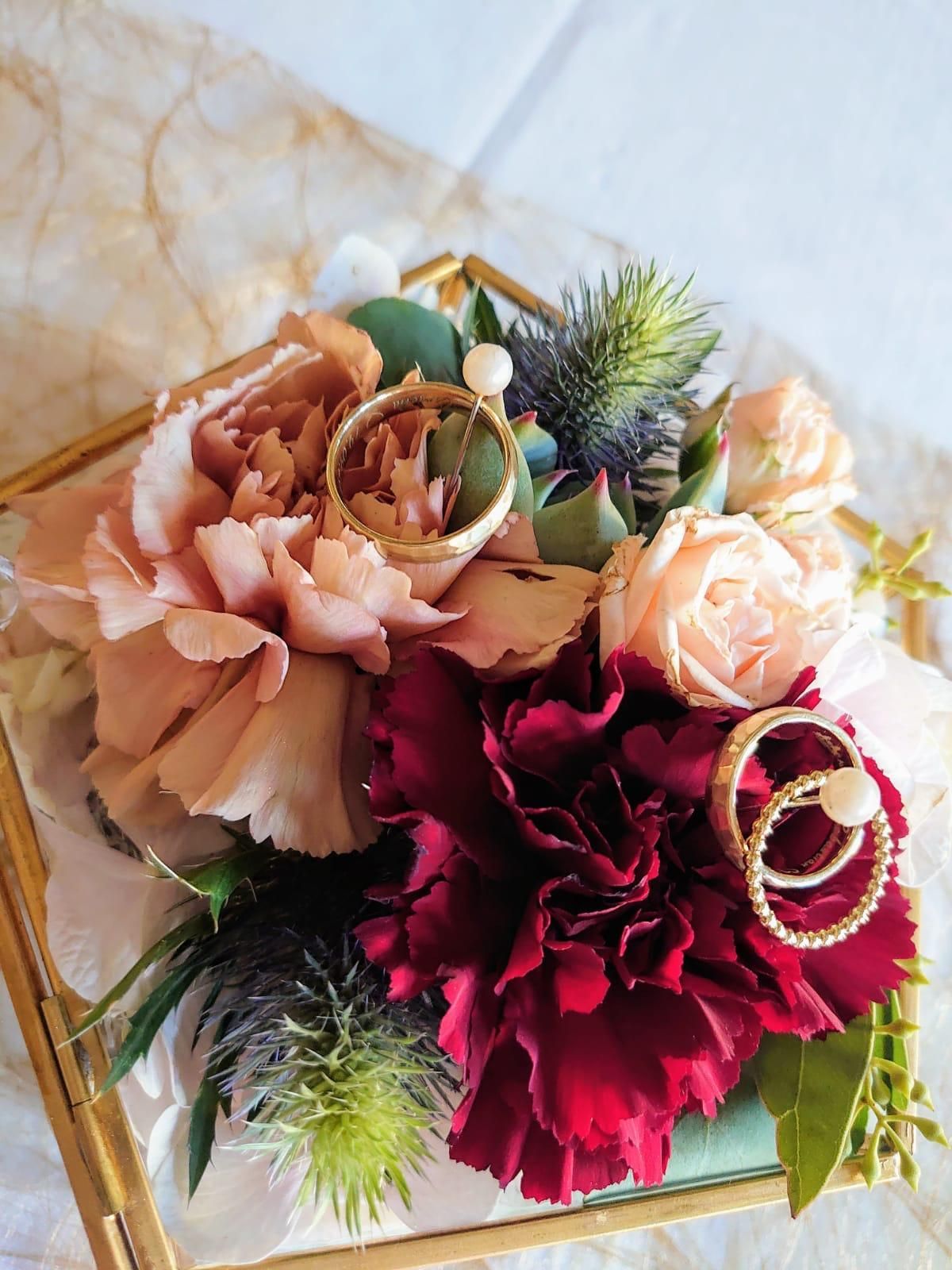 Ringschachtel mit Blumenarrangement: burgunder- und pfirsichfarbene Blumen, goldene Ringe und grüne Akzente.
