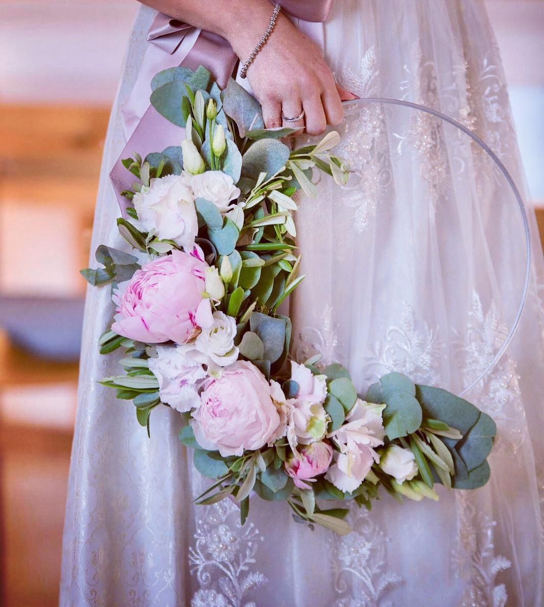 Braut hält Blumenstrauß aus rosa Pfingstrosen, weißen Blumen, Eukalyptus und Schleife.