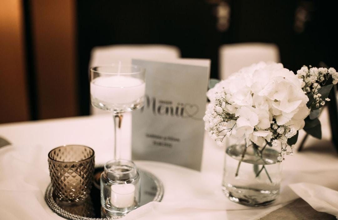 Tischdekoration für den Hochzeitsempfang: Kerze, Blumenstrauß, Menükarte.