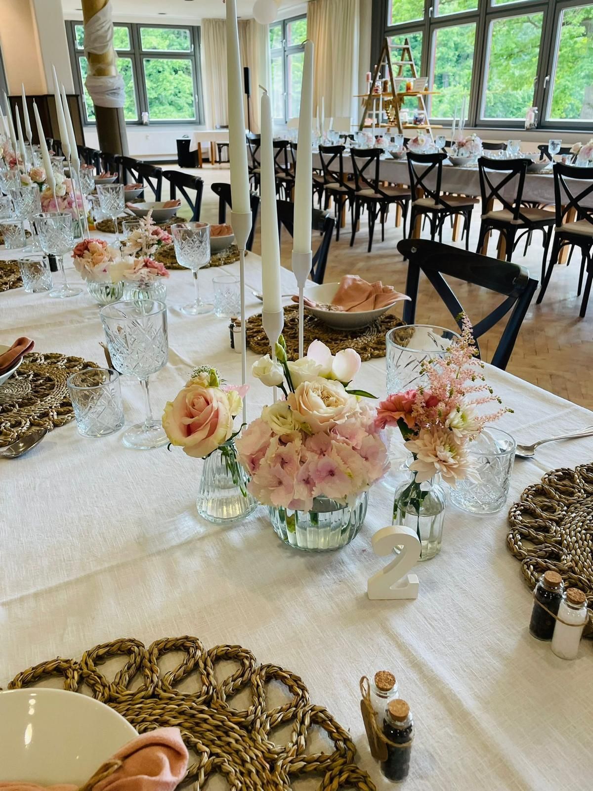 Elegante Tischdekoration mit Blumen, Kerzen und gewebten Tischsets, bereit für eine Feier in einem Essbereich.