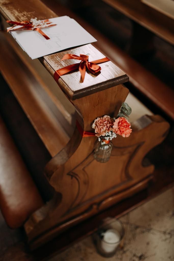 Mit Blumen und Bändern geschmückte Kirchenbank aus Holz mit einer Notiz.