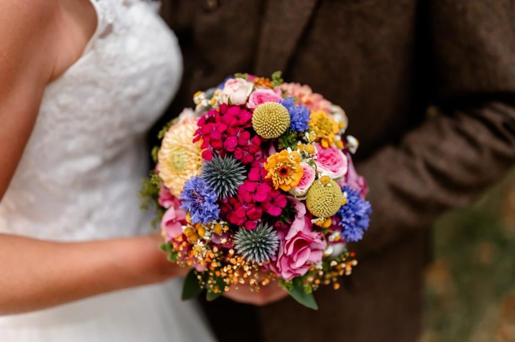 Braut und Bräutigam halten einen bunten Brautstrauß.