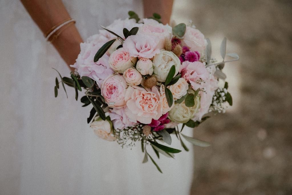 Braut hält im Freien einen Strauß rosa und weißer Blumen.