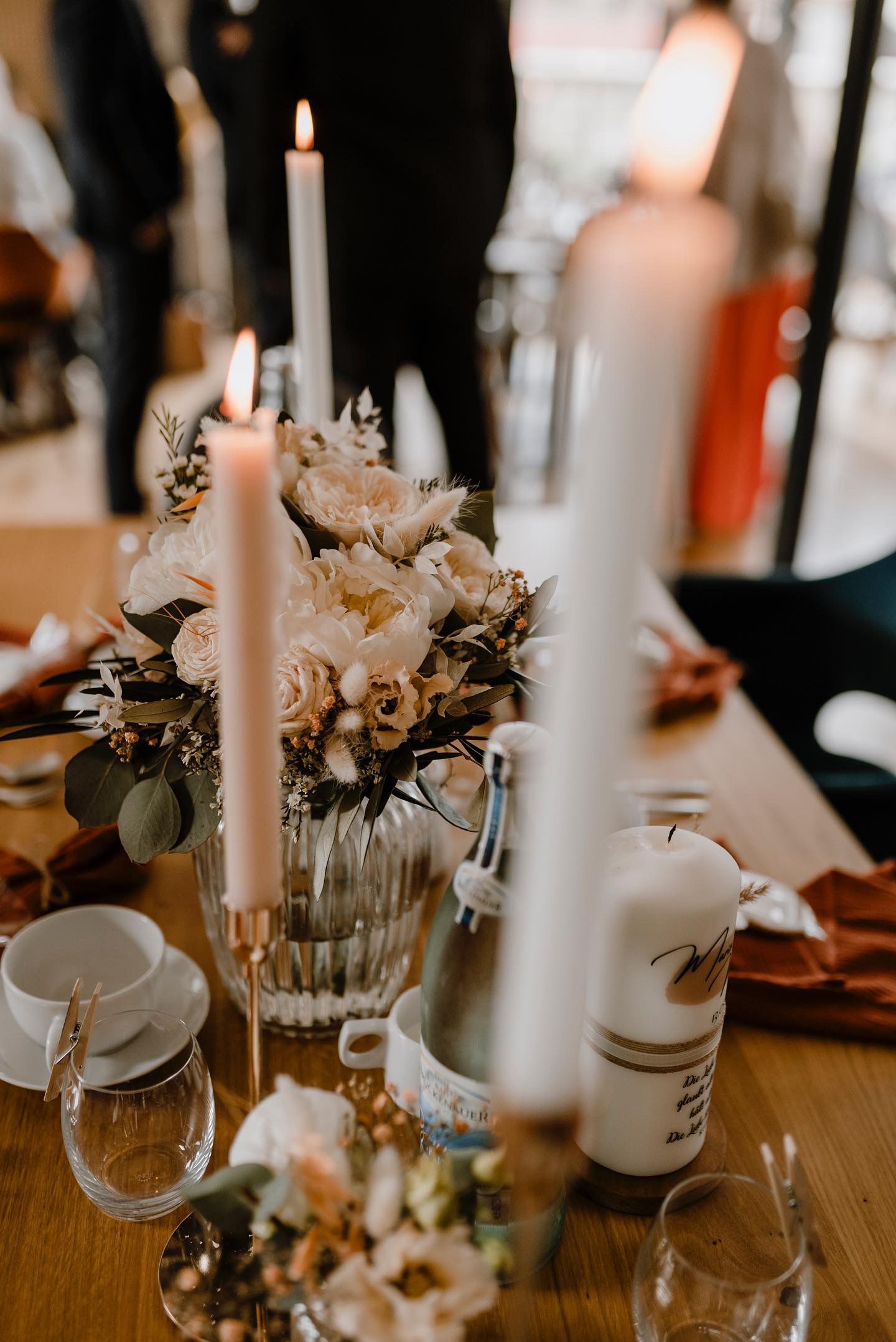 Hochzeitstischdekoration mit Blumen, Kerzen und Gläsern.