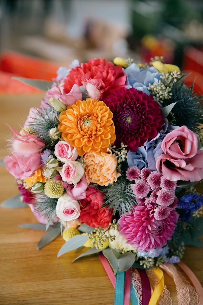 Bunter Hochzeitsstrauß mit verschiedenen Blumen und Bändern.