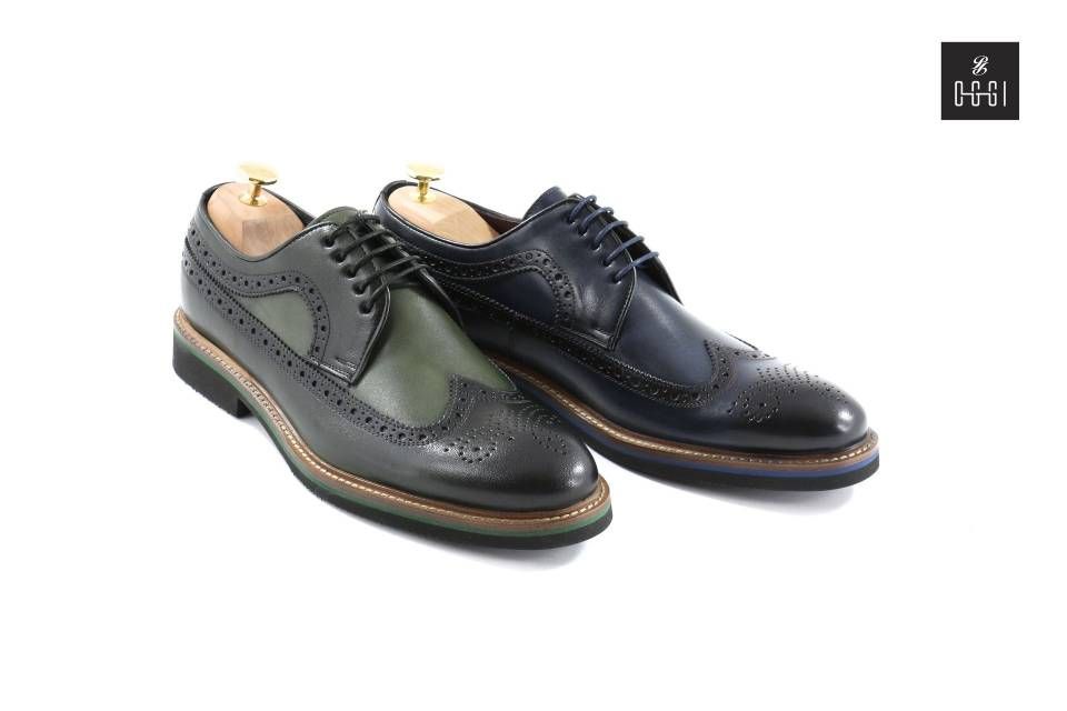 Une paire de chaussures brogue noires et vertes sur fond blanc.
