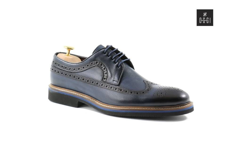 Une paire de chaussures bleues avec un porte-chaussures en bois sur fond blanc.