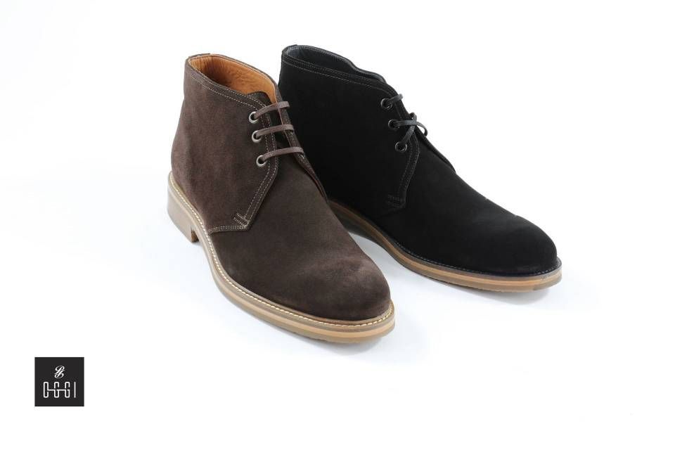 Une paire de bottines chukka marron et noires sur fond blanc