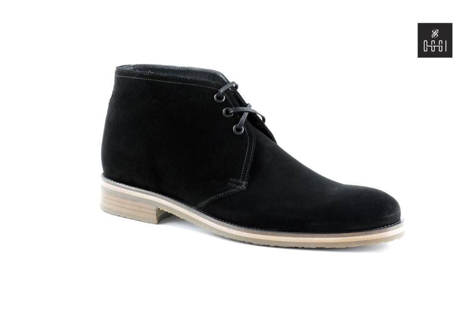 Une paire de bottines chukka en daim noir sur fond blanc
