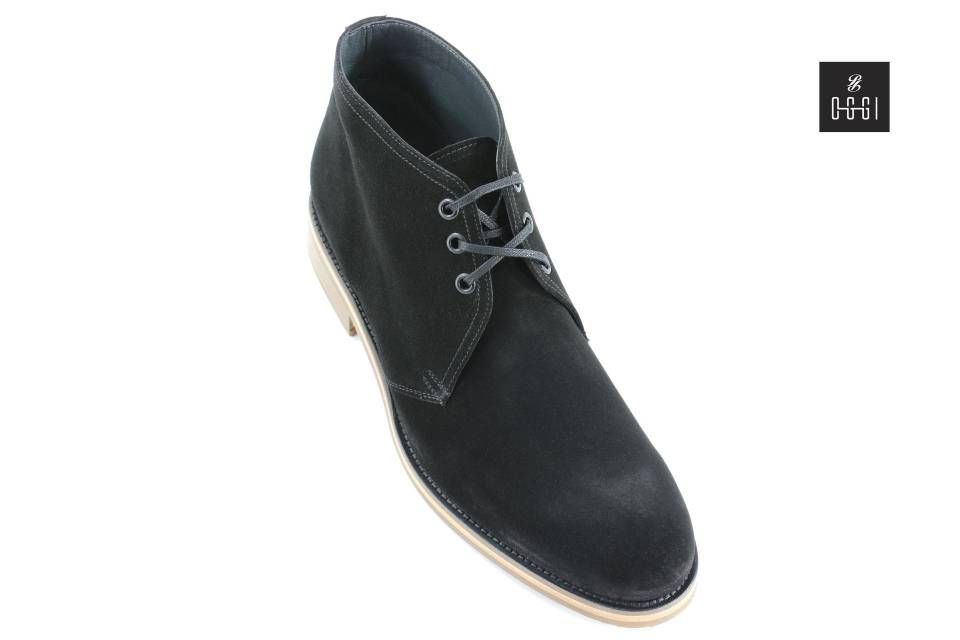 Une paire de bottines chukka en daim noir sur fond blanc