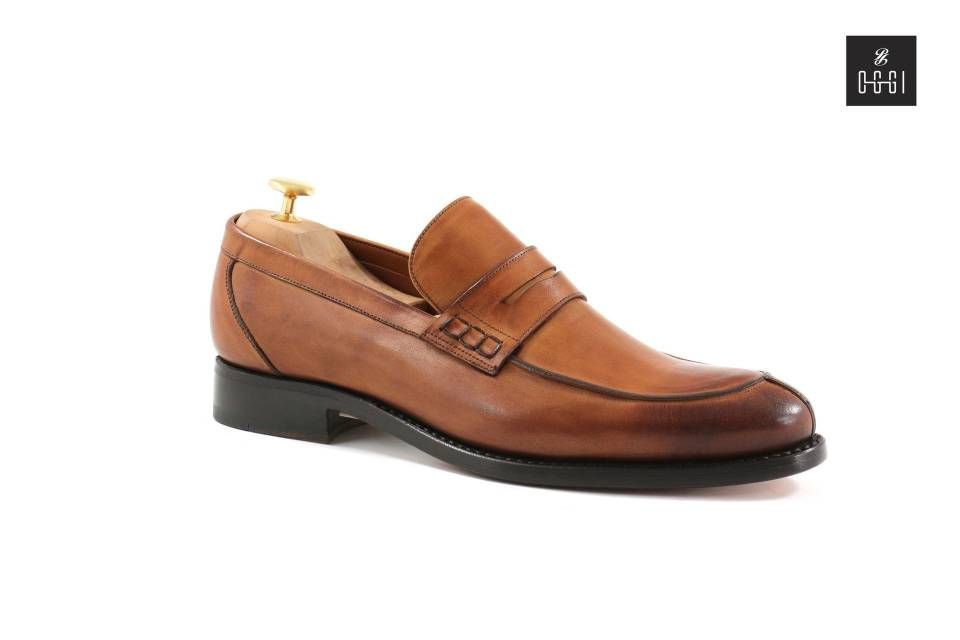 Une paire de mocassins en cuir marron sur fond blanc