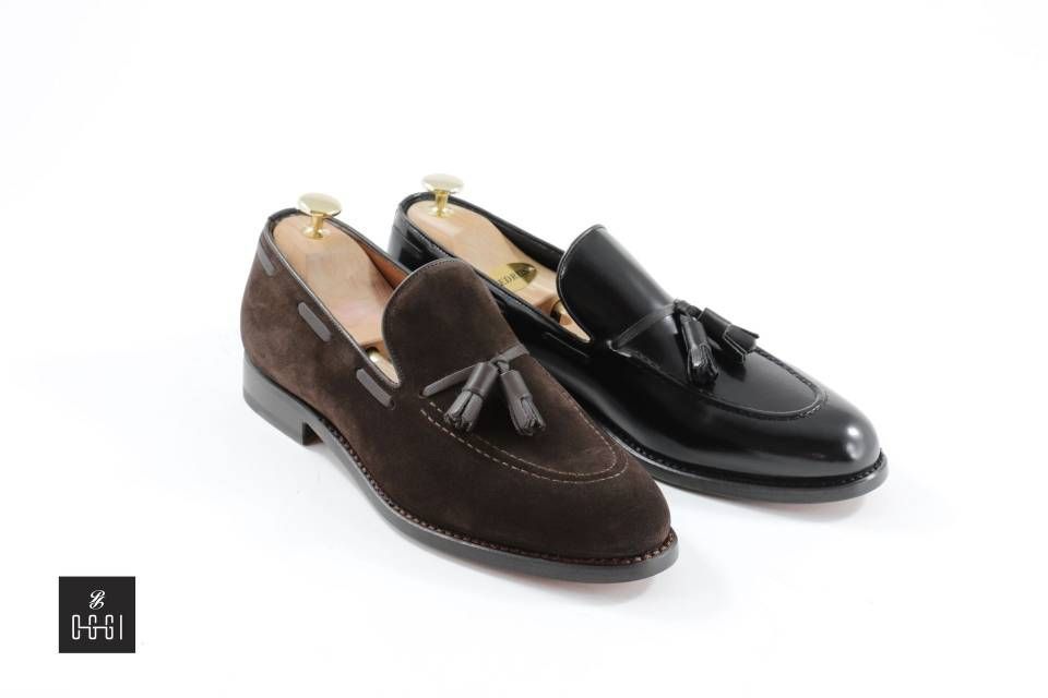 Une paire de mocassins marron et noirs à pompons sur fond blanc