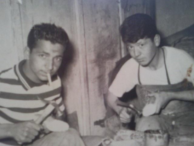 photo en noir et blanc de deux hommes en train de réparer des chaussures