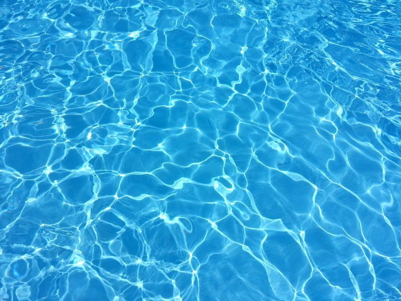 Agua de piscina azul con reflejos del sol.