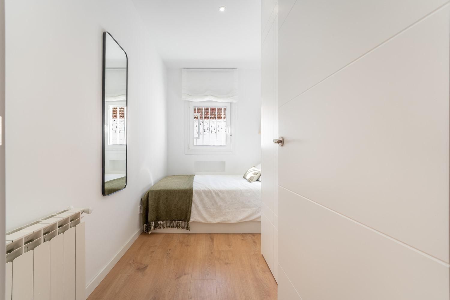 Un dormitorio pequeño con una cama y un espejo en la pared.