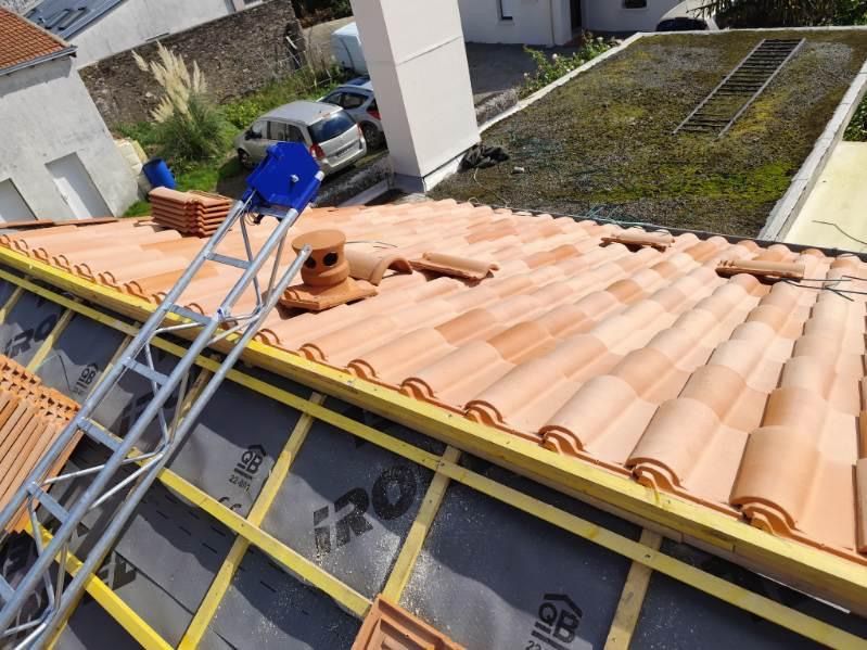 Toiture en tuiles d'argile orange ; échelle et matériaux visibles.