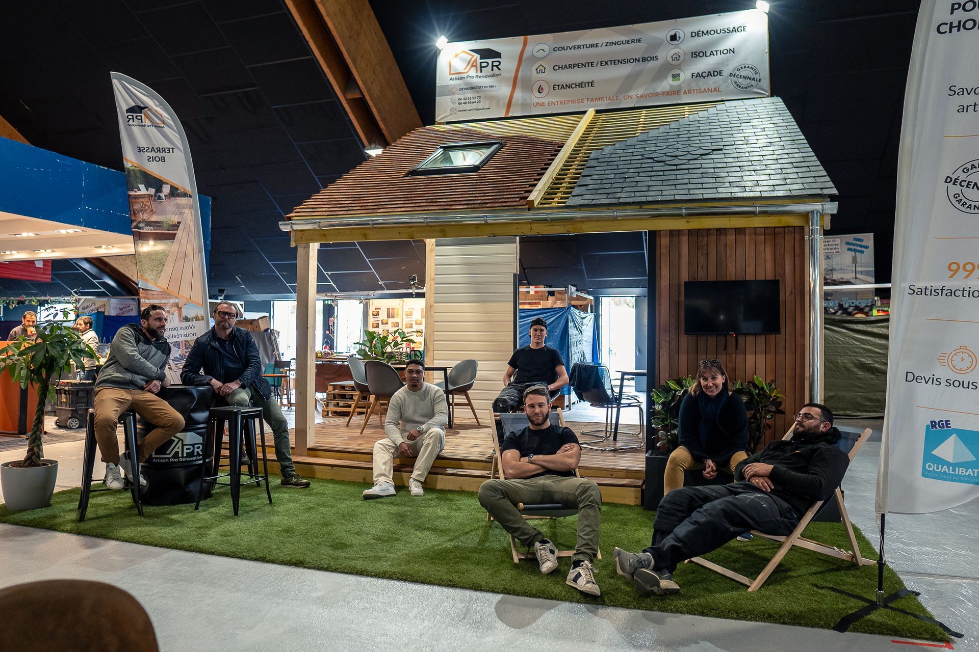 Équipe au Salon de l'Habitat avec une maison en bois en miniature.