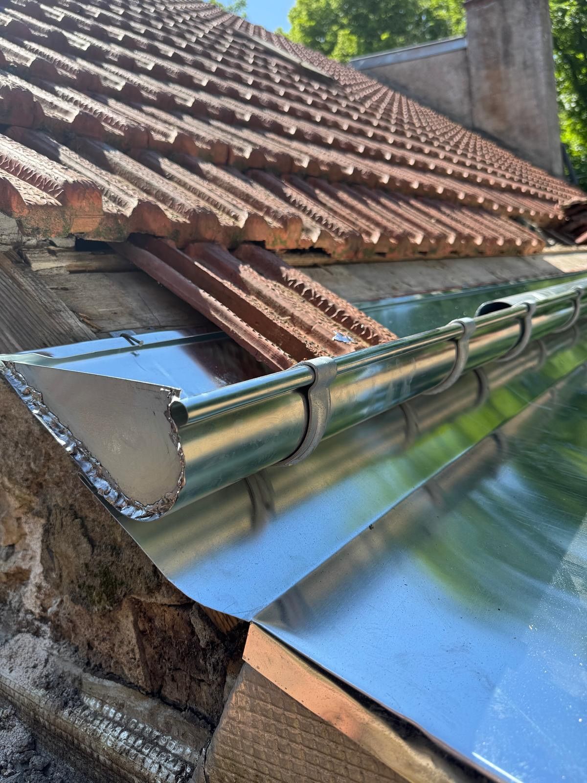 Nouvelle gouttière en acier galvanisé installée sur un toit en tuiles.