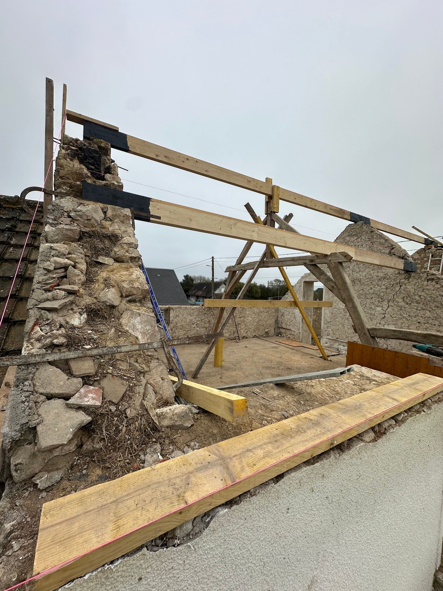 Chantier : bâtiment en pierre en cours de rénovation, poutres en bois et échafaudages visibles.