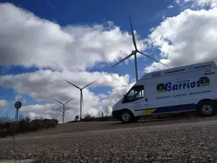 Aerogeneradores con una furgoneta de la empresa en una carretera bajo un cielo nublado.