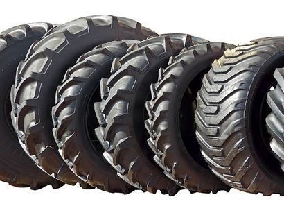 Neumáticos de tractor en fila, con dibujo profundo, probablemente para uso agrícola.