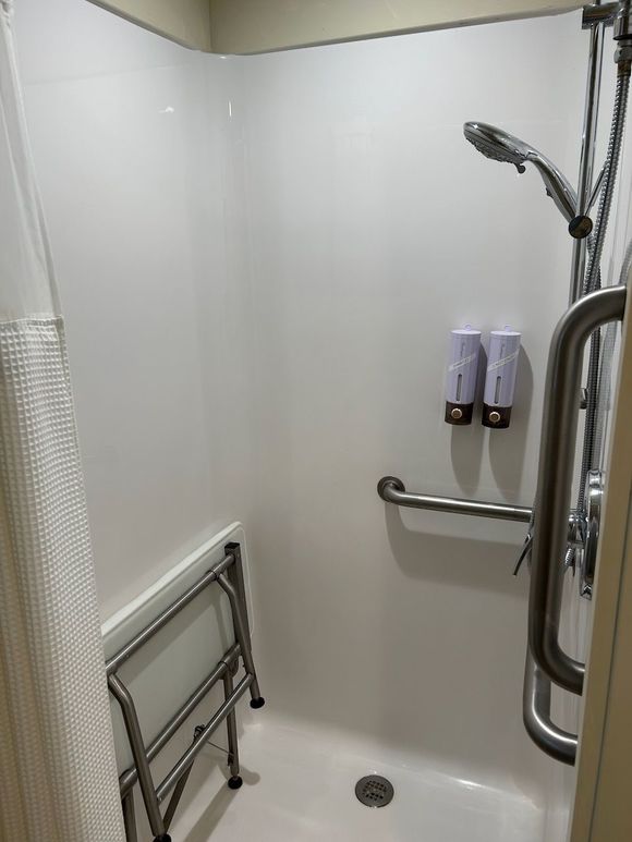 There is a walker in the shower with a shower head.