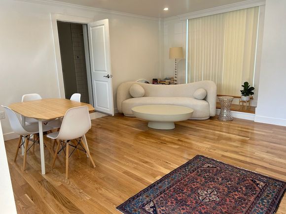 A living room with a couch , table , chairs and rug.