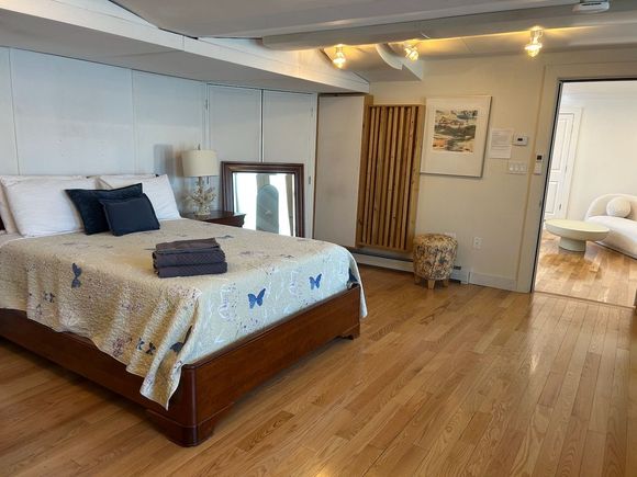 A bedroom with a large bed and hardwood floors