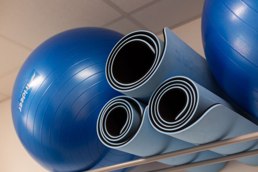 Blaue Gymnastikbälle und zusammengerollte Yogamatten lagen gestapelt auf einem Regal.