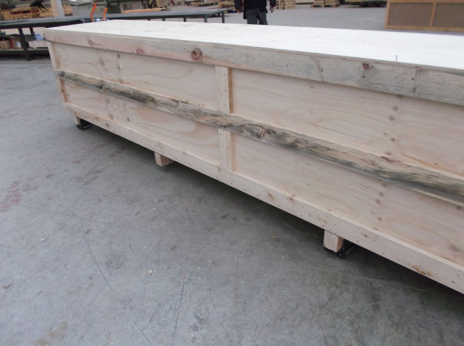 Una gran caja de madera con ruedas está en el suelo.
