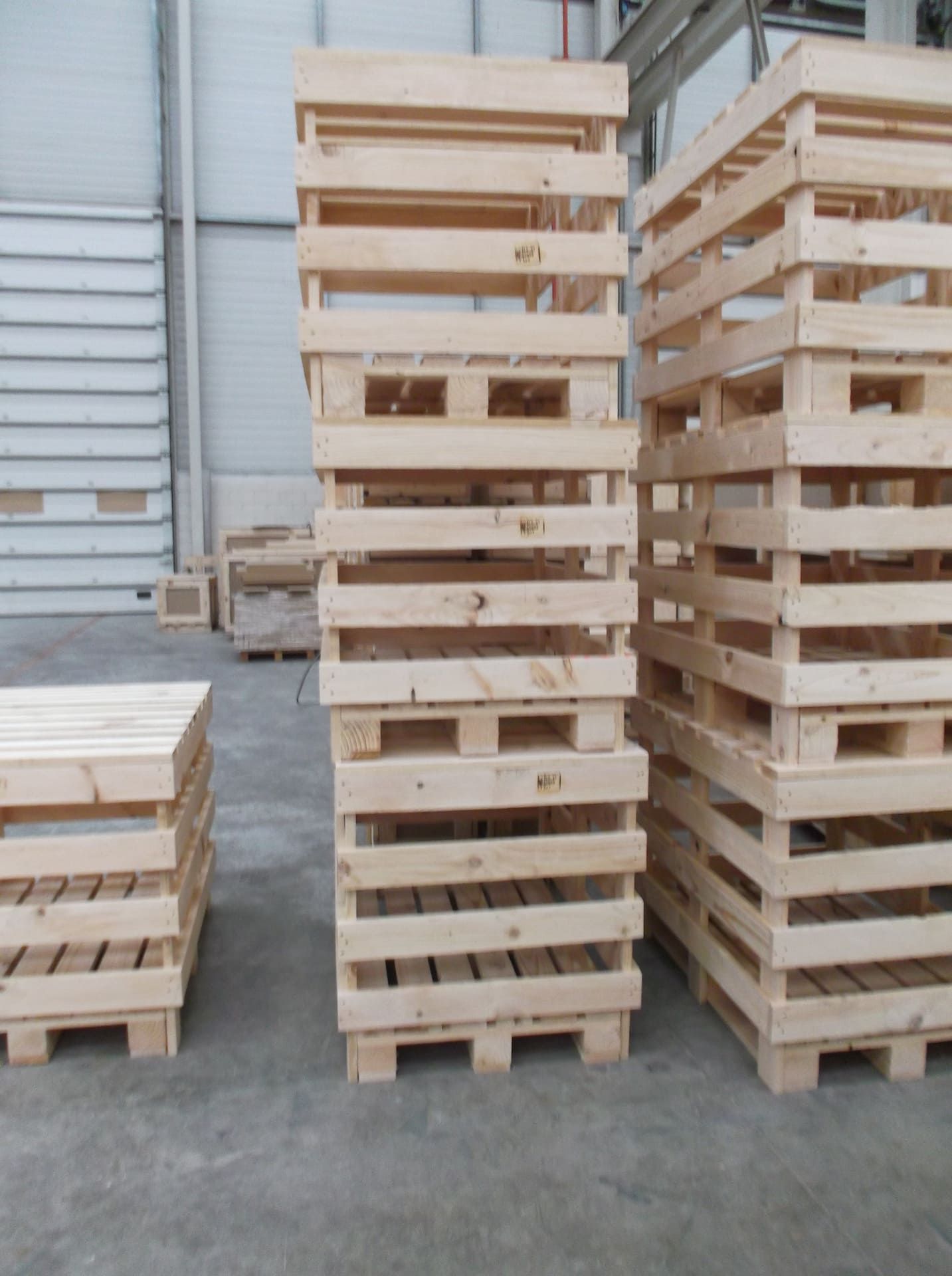 Tres pilas de palets de madera en un almacén