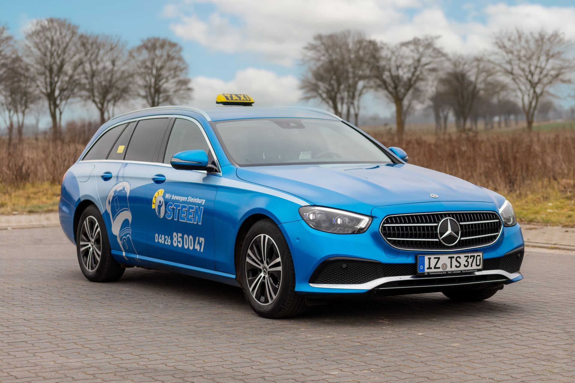 Ein blaues Mercedes-Benz-Taxi steht am Straßenrand.