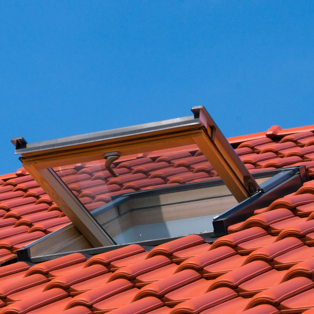 Puits de lumière ouvert sur un toit de tuiles rouges.