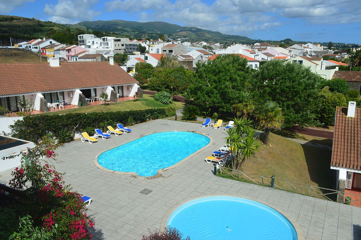 Piscinas e vista para a cidade, com casas e montanhas ao fundo.