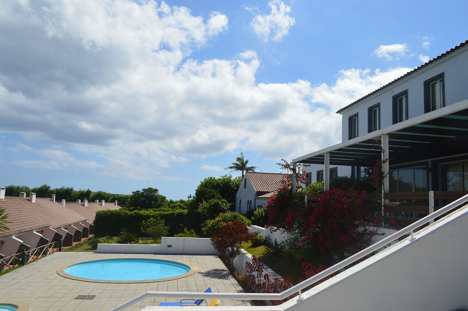 Piscina e edifícios brancos sob um céu parcialmente nublado.