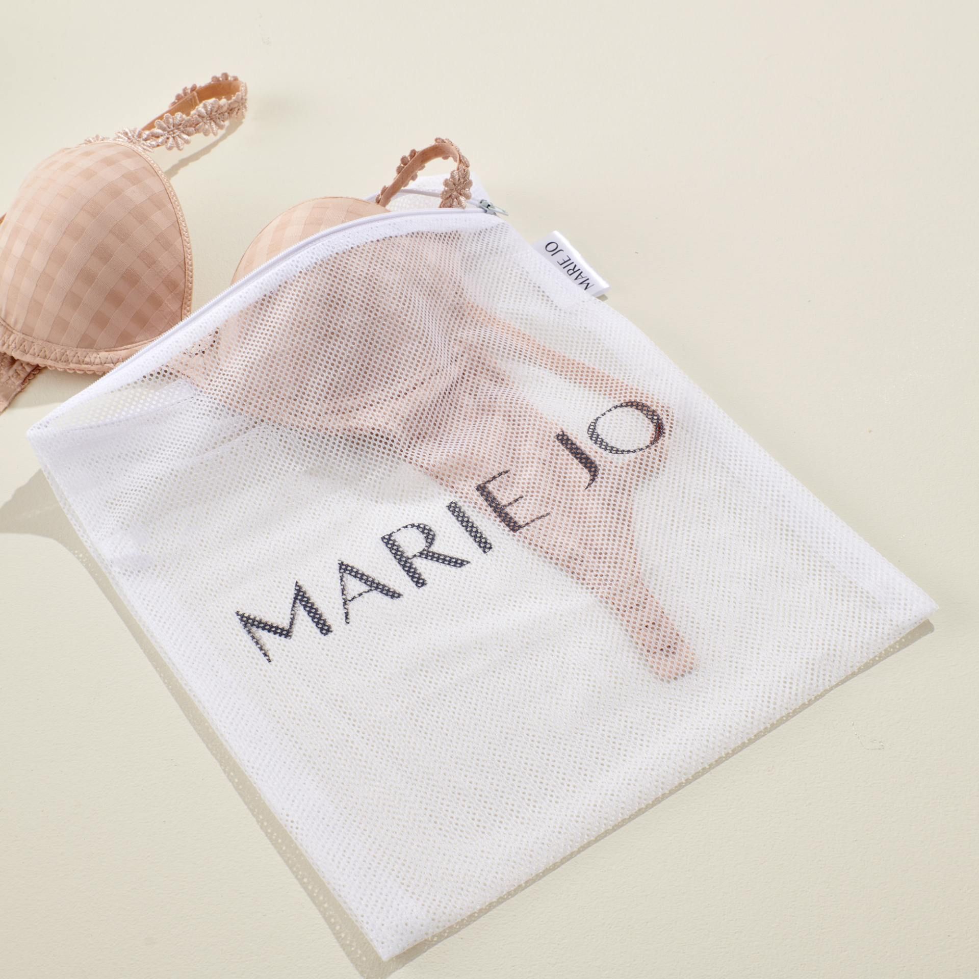 Beiger BH in einem weißen Wäschenetz mit dem Schriftzug „MARIE JO“ auf hellbeigem Untergrund.