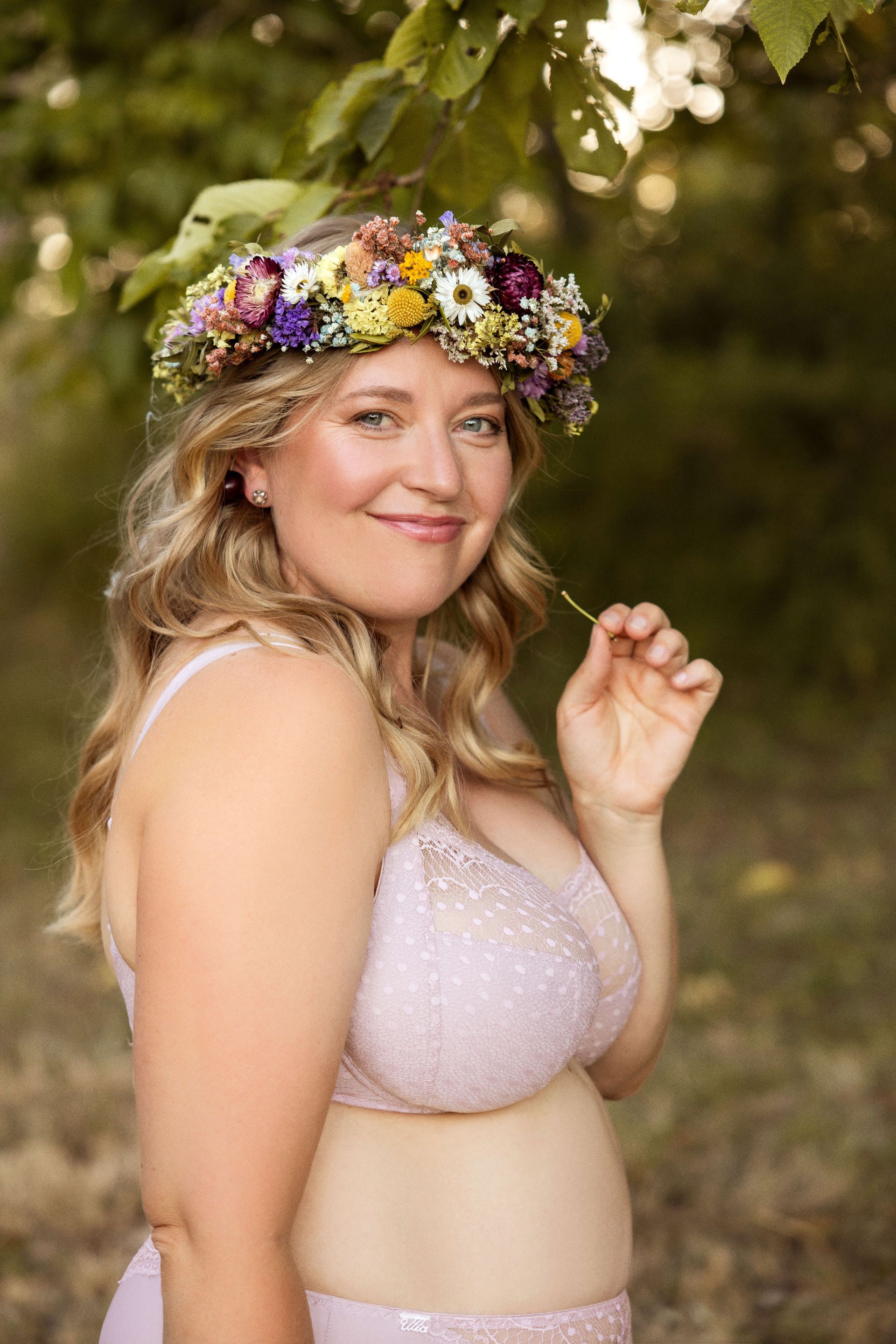 Frau in Sportkleidung, die mit Wasserflasche und Sporttasche drinnen ruht und lächelt.