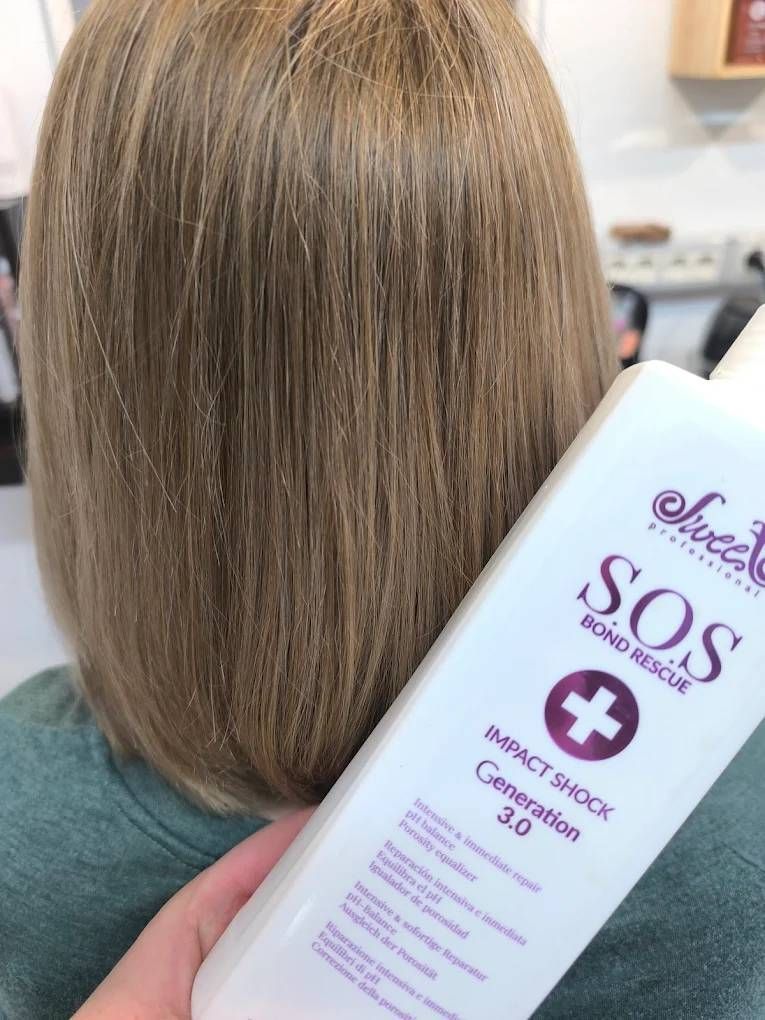 Un barbero le corta la barba a un hombre con tijeras. El hombre está reclinado en una silla de peluquería.