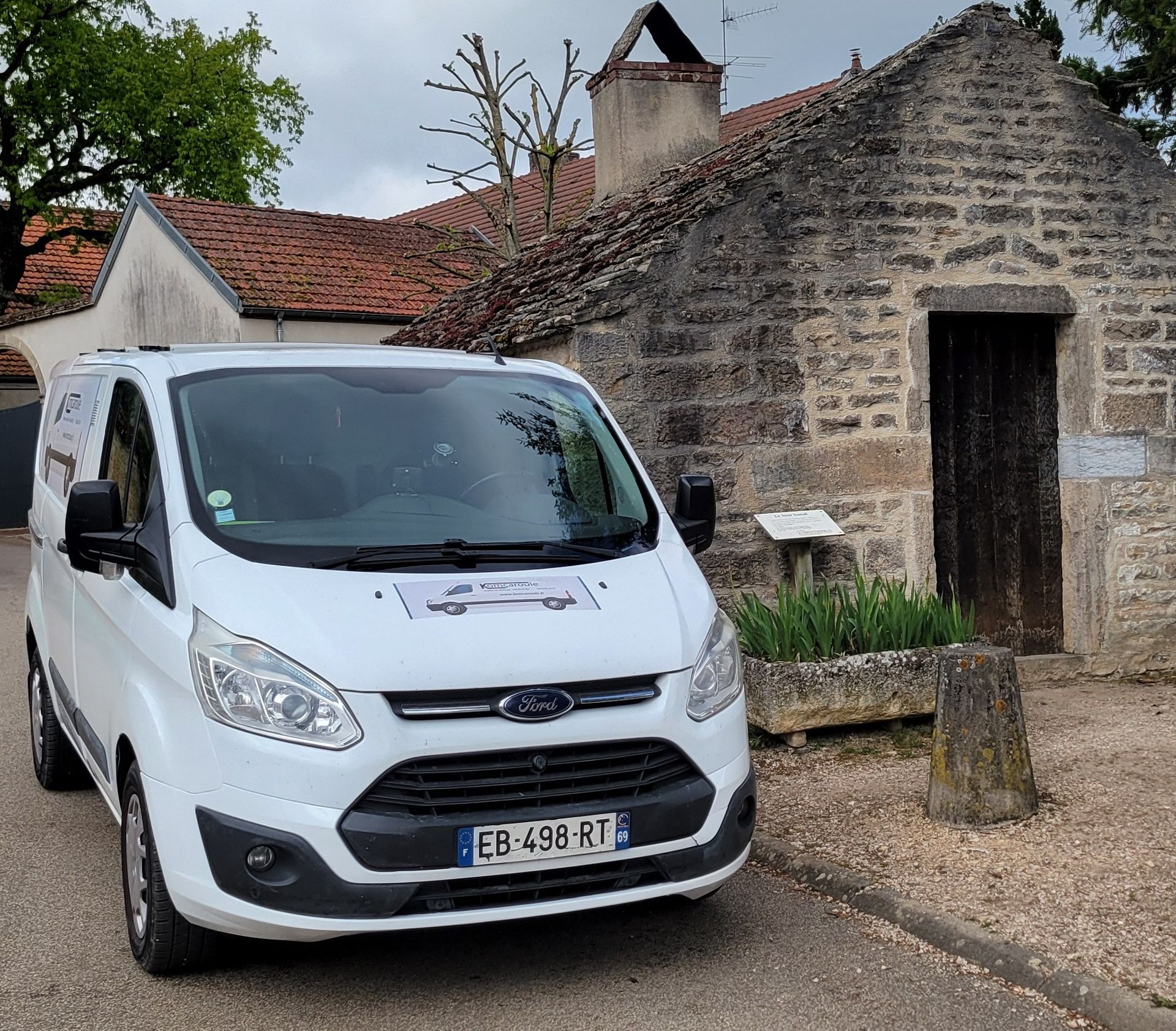 Deux fourgonnettes utilitaires grises sont garées sur un parking recouvert de sable.