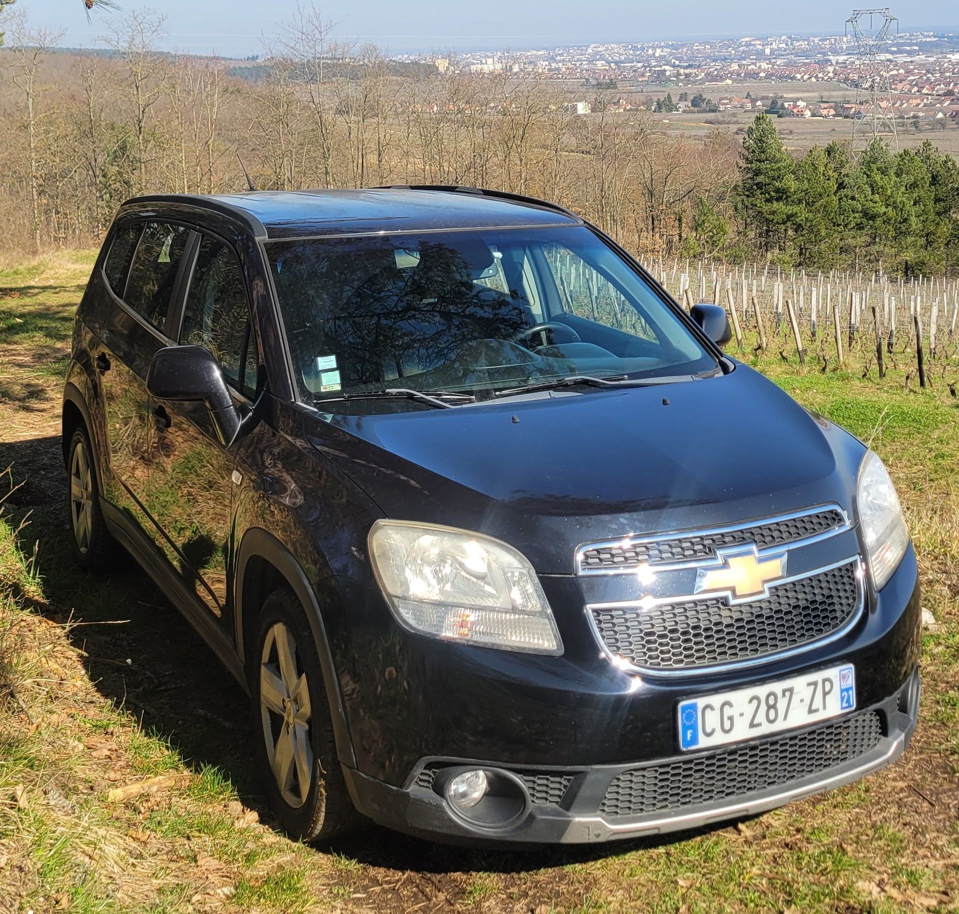 Une camionnette Peugeot de couleur noire garée sur une plage de sable au lever du soleil.