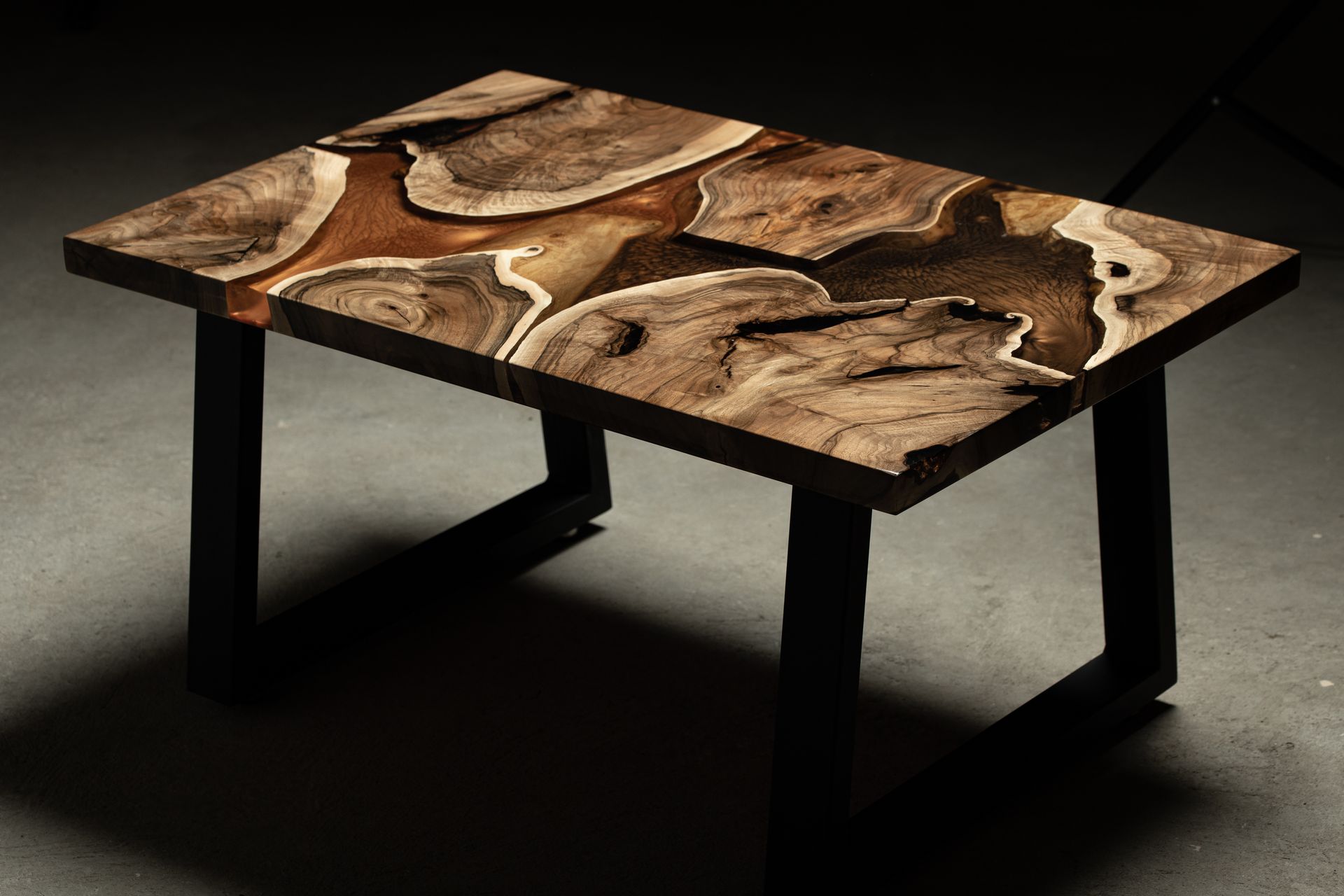 Ein Holztisch mit Holzplatte und Metallbeinen steht auf einem Betonboden.