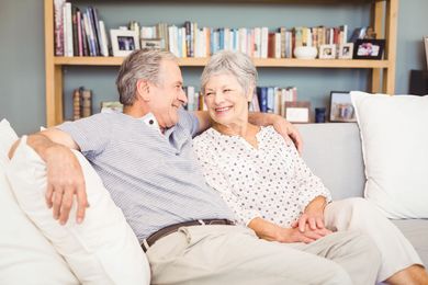 Ein älteres Ehepaar sitzt auf einer Couch im Wohnzimmer.