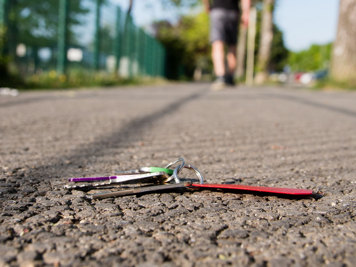 Des mains manipulent une clé et une poignée sur une porte de coffre-fort en métal gris foncé.