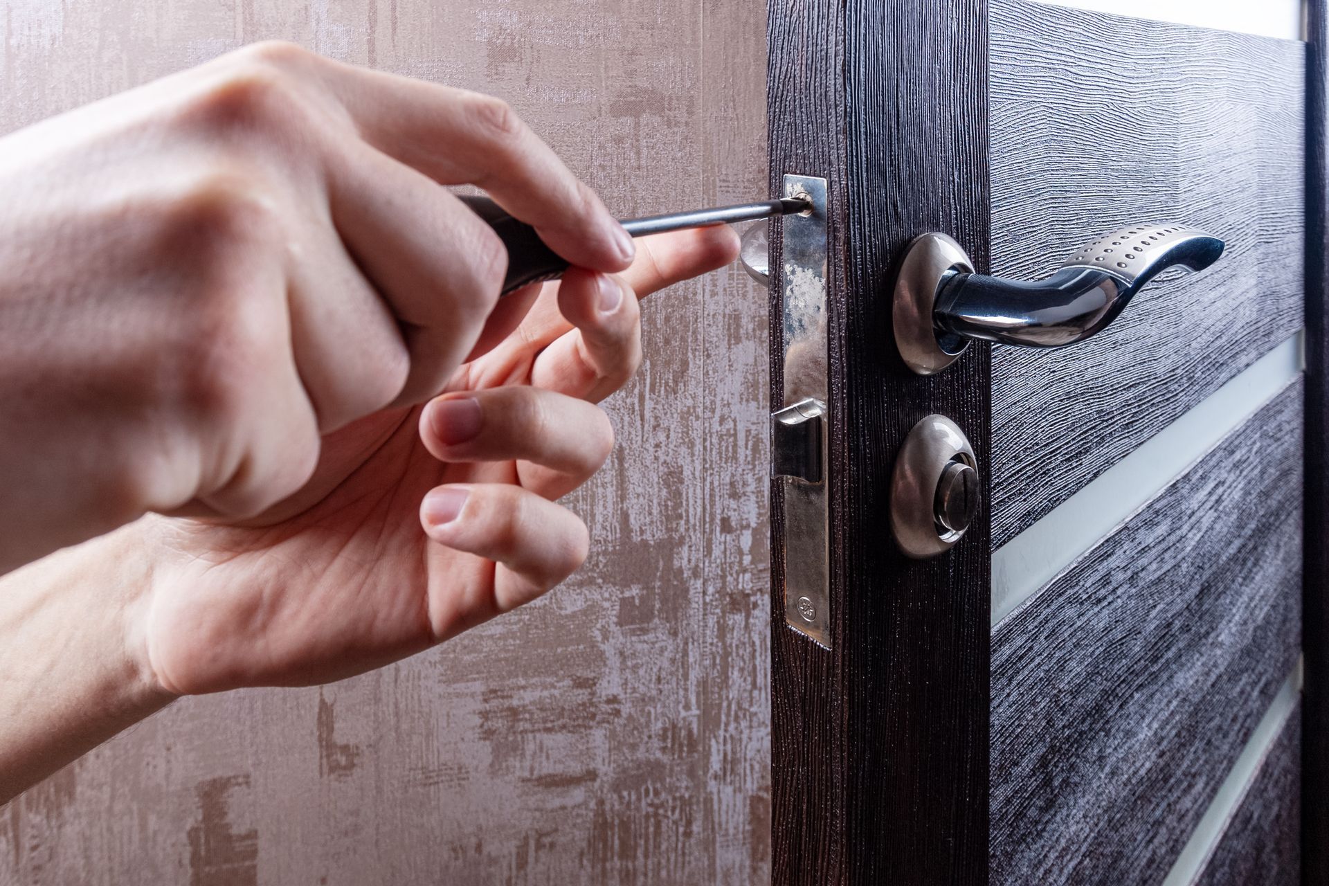 Main utilisant une clé pour déverrouiller une porte d'entrée en bois sombre