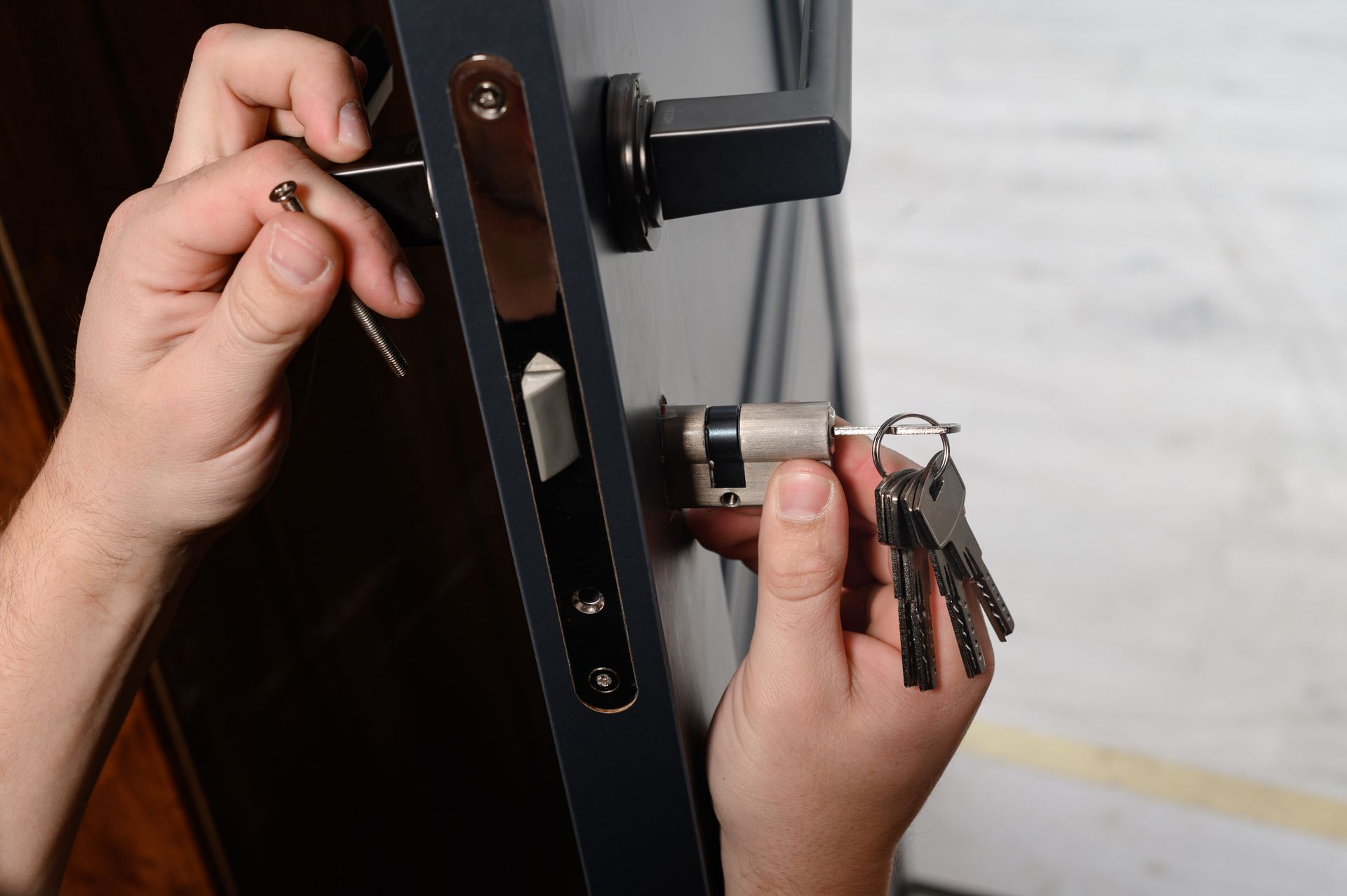 Gros plan de mains déverrouillant une porte noire avec un porte-clés.