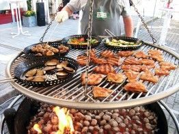 Ein Mann grillt Fleisch und Gemüse.