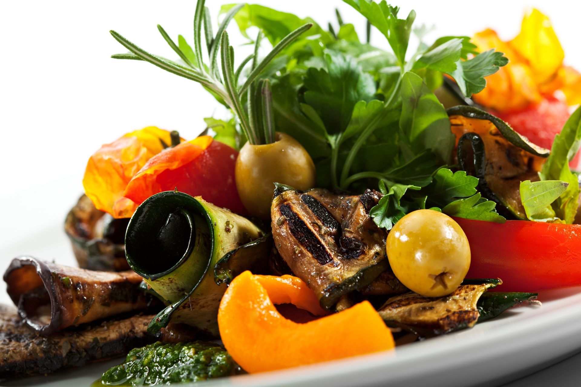 Ein weißer Teller mit gegrilltem Gemüse und Oliven